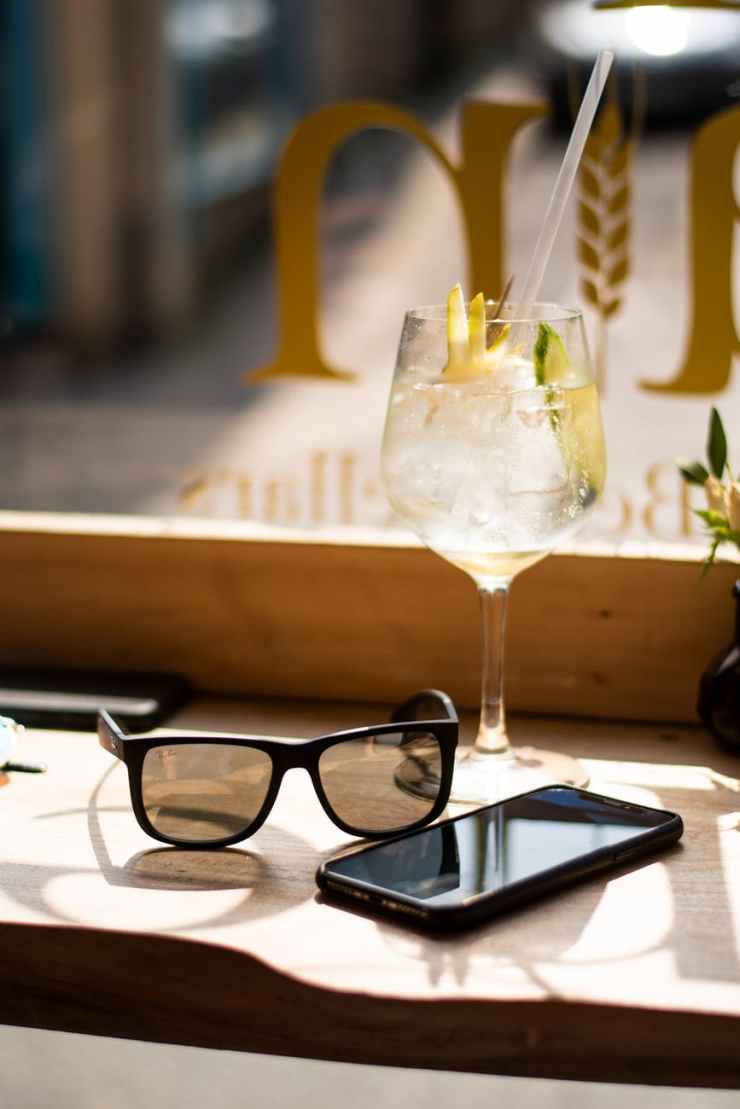 wine glass beside android smartphone and sunglasses